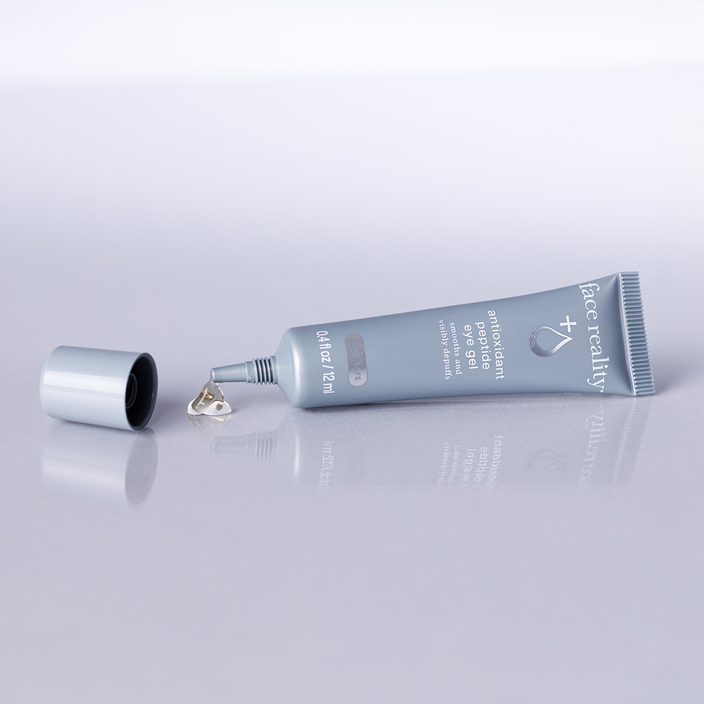 Face Reality Antioxidant peptide eye gel tube lying flat against a reflective light surface.
