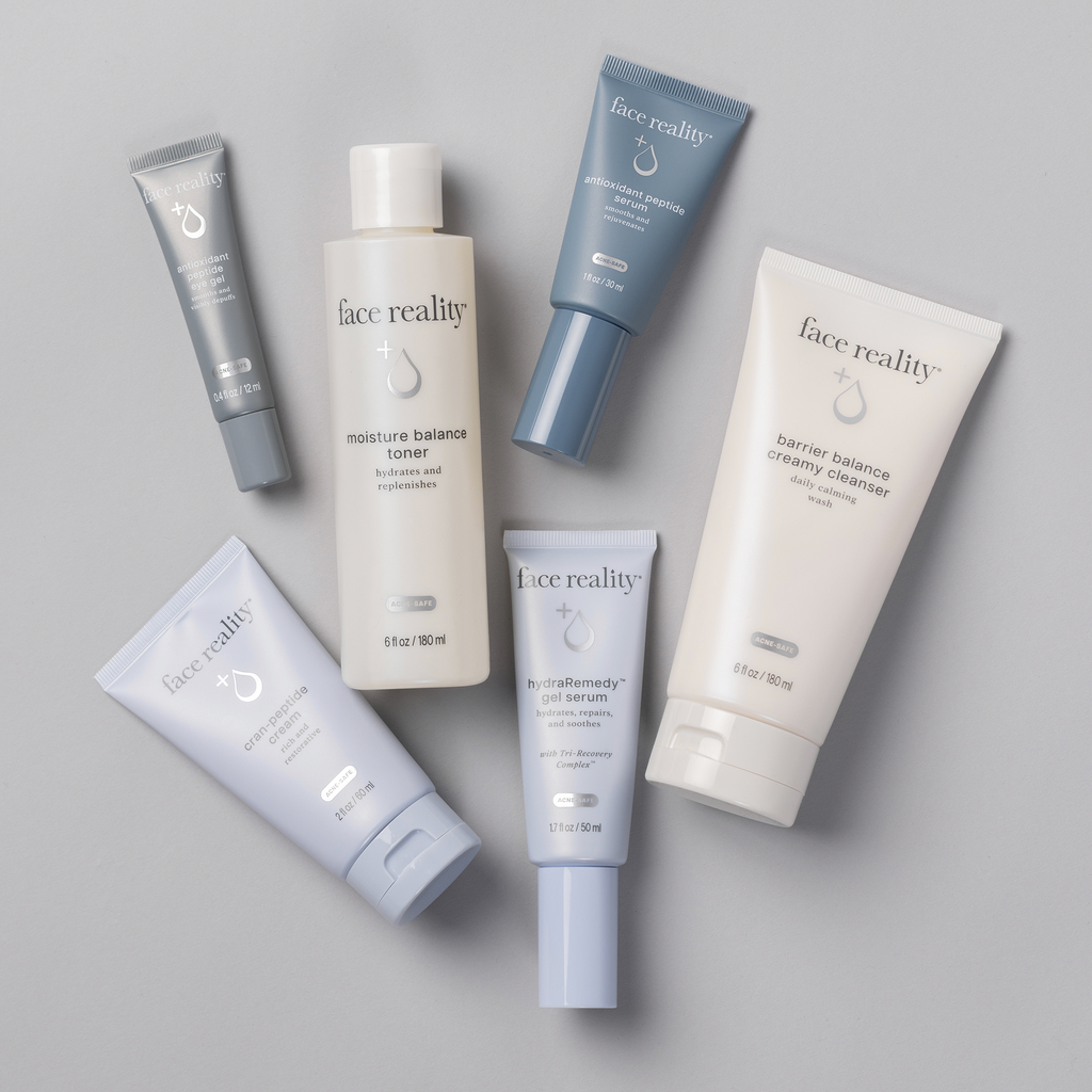 Face Reality Deluxe Age Defense Kit showing Antioxidant Peptide Eye Gel, hydraRemedy™ Gel Serum, Barrier Balance Creamy Cleanser, Antioxidant Peptide Serum, Moisture Balance Toner, and Cran-Peptide Cream laying flat against light background.