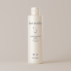 White bottle of Face Reality calming facial toner against light beige background