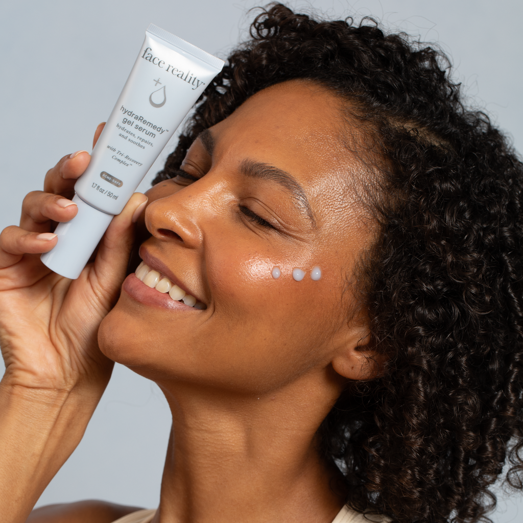 Person holding Face Reality hydraRemedy™ Gel Serum next to face against light background
