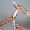 Three hands holding Face Reality hydraRemedy™ Gel Serum in different sizes against light background