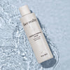 Face Reality moisture balance toner bottle laying flat against light blue pool of water