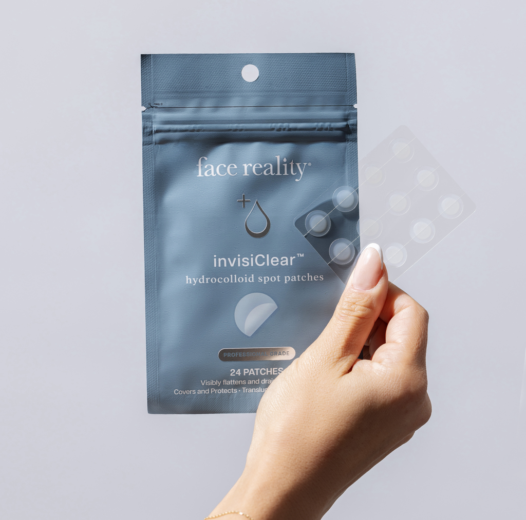 Hand holding Package of Face Reality invisiClear hydrocolloid spot patches on a light background